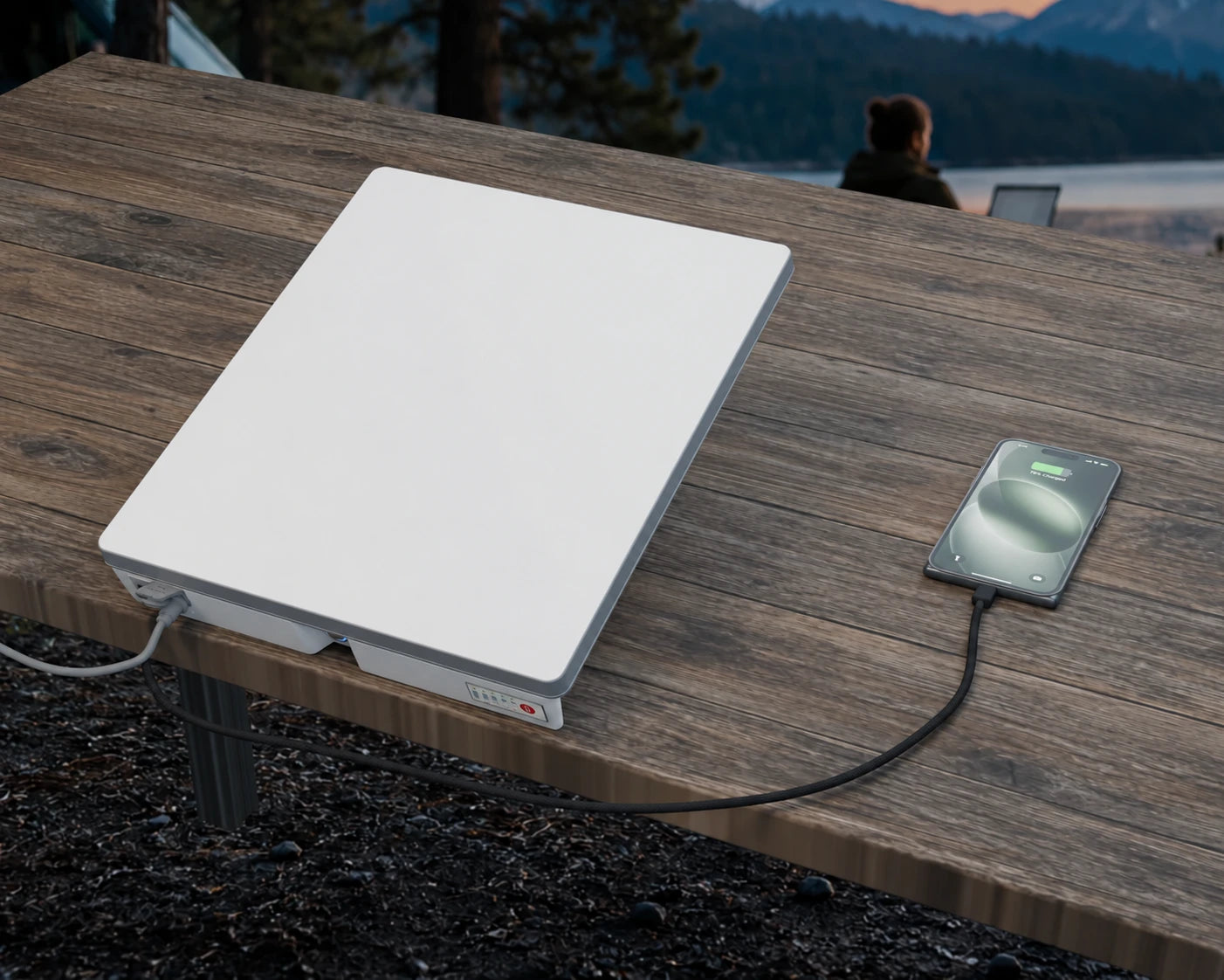 One Mini with its mounted battery taking DC input from outside the frame while its black braided USB-C cable charges an iPhone